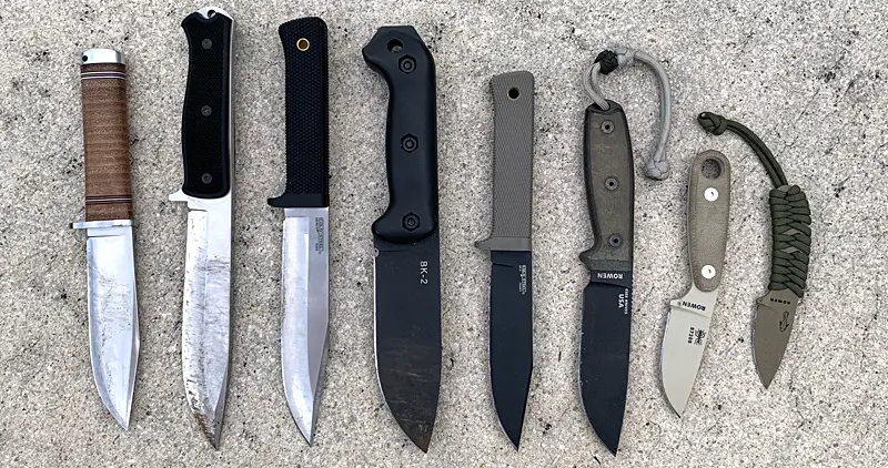 A group of survival knives on the ground. Fallkniven, Cold Steel, ESEE, and more