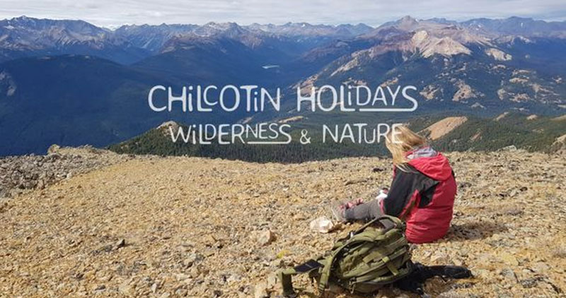 Chilcotin Holidays Wilderness & Nature: a woman sitting on a hill with mountains in the background