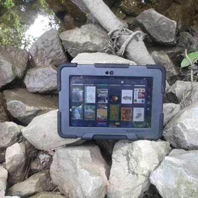 Kindle with a protective case sitting on some rocks