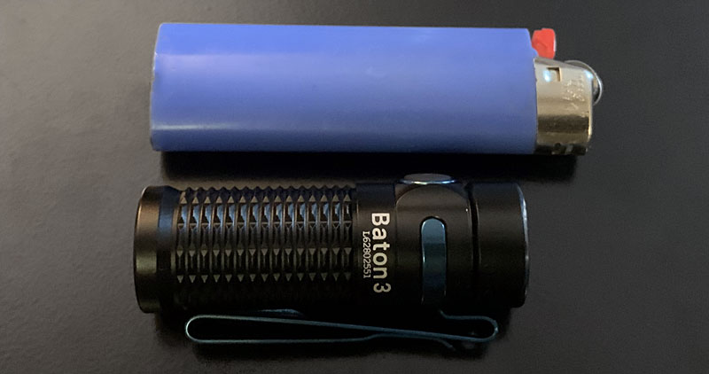 Olight Baton Warrior Mini 2 next to a lighter for size comparison