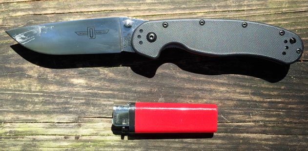 Ontario Company RAT Folding Knife open next to a lighter for size comparison