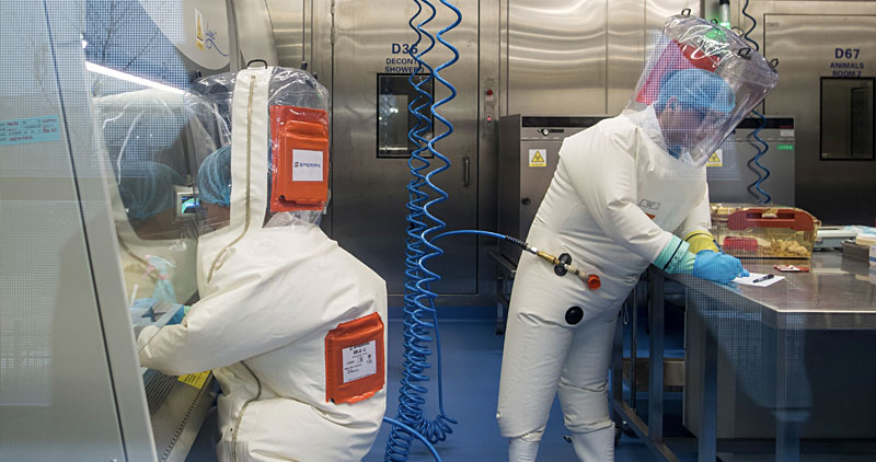 Virology lab scientists wearing pressurized suits