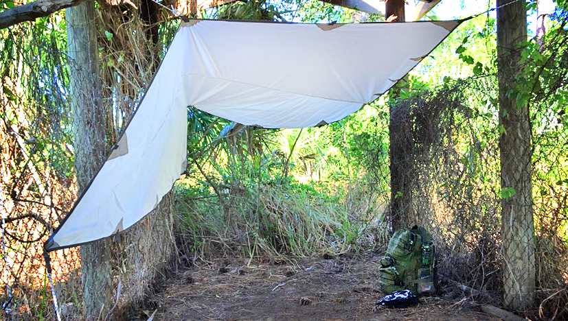 Rolling Fox Tarp Shelter setup under shelter with a backpack on the floor