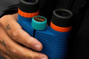 Nocs Provisions Standard Issue binoculars held outdoors while scanning a hazy horizon for wildfire smoke and grid emergencies