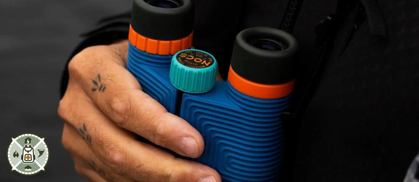 Nocs Provisions Standard Issue binoculars held outdoors while scanning a hazy horizon for wildfire smoke and grid emergencies
